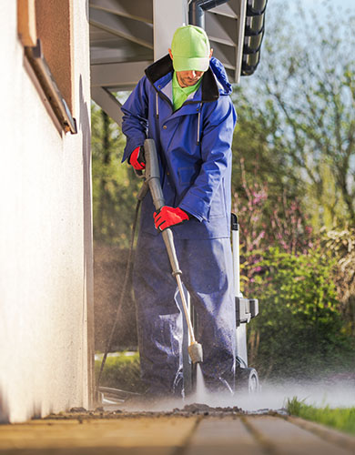 A man in a blue suit and gloves is cleaning the interior of a house, focusing on tidying up surfaces.